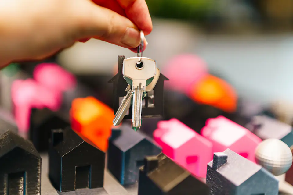 House keys for a new home in the North East Hand holding a set of house keys above small model houses