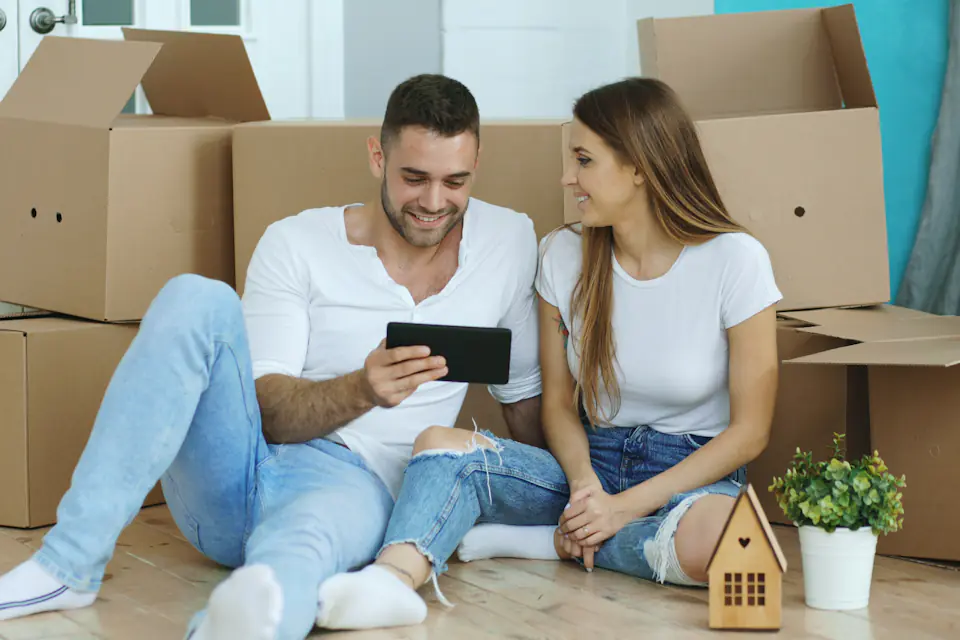 Couple sitting among moving boxes looking at a tablet together