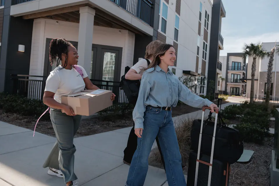 Young people carrying boxes and luggage outside a building entrance