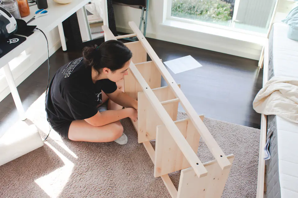 Furniture assembly in Newcastle Person kneeling on the floor assembling a wooden shelving unit