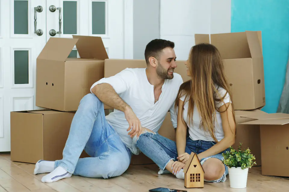 Couple sitting on the floor among moving boxes in their new home