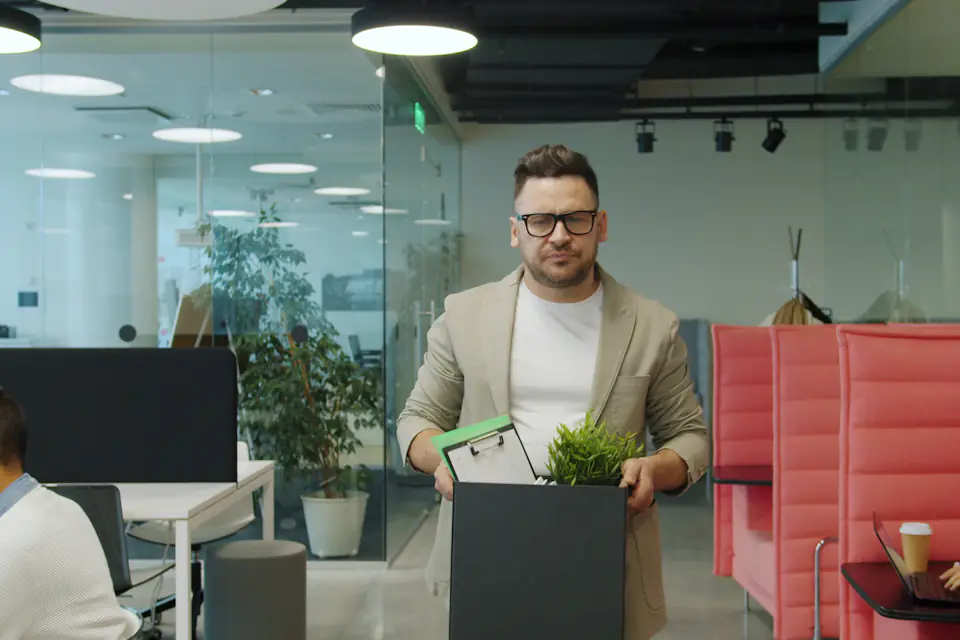 Staff settling into new offices after a Newcastle office move Man carrying a box with a plant through a modern office with red seating