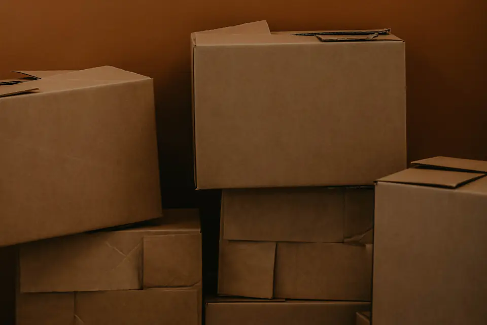Moving boxes representing removal volume Neat stack of brown cardboard boxes against a warm brown background